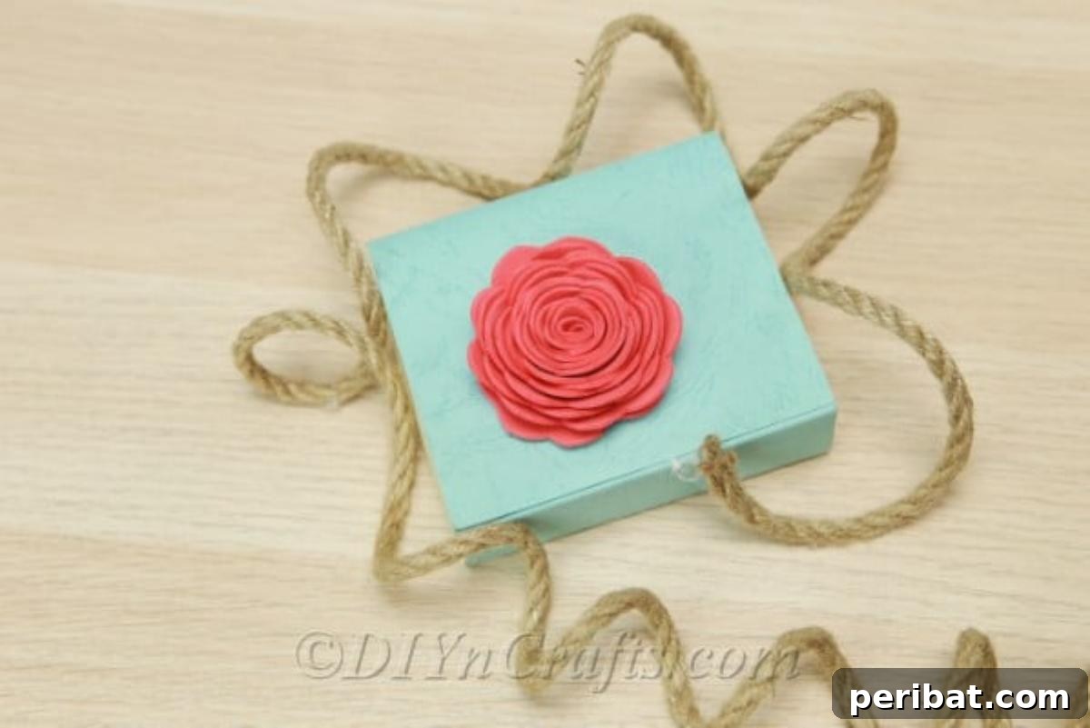 A delicate foam flower resting on a decorated box, showcasing its potential as a craft embellishment.