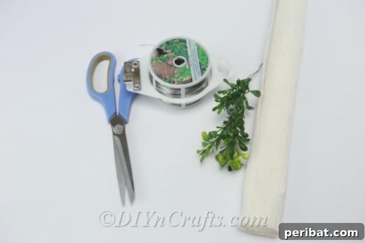 A neatly arranged collection of craft supplies, including tissue paper, scissors, hot glue gun, floral wire, and faux branches, laid out for making tissue paper flowers.