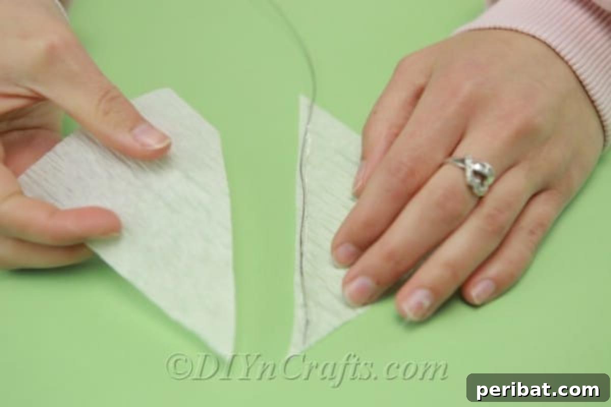 A crafter meticulously gluing the edge of a delicate tissue paper triangle onto a floral wire, ensuring a secure bond.