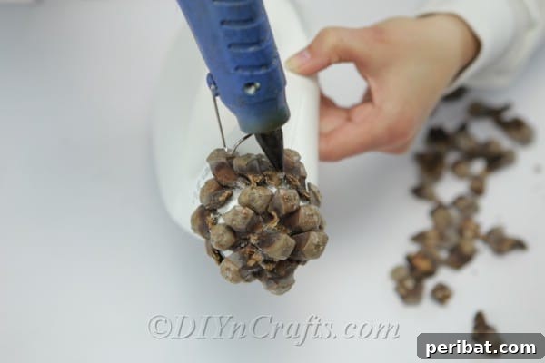 Gluing pinecone pieces to the lid of a detergent bottle, creating a charming, textured roof