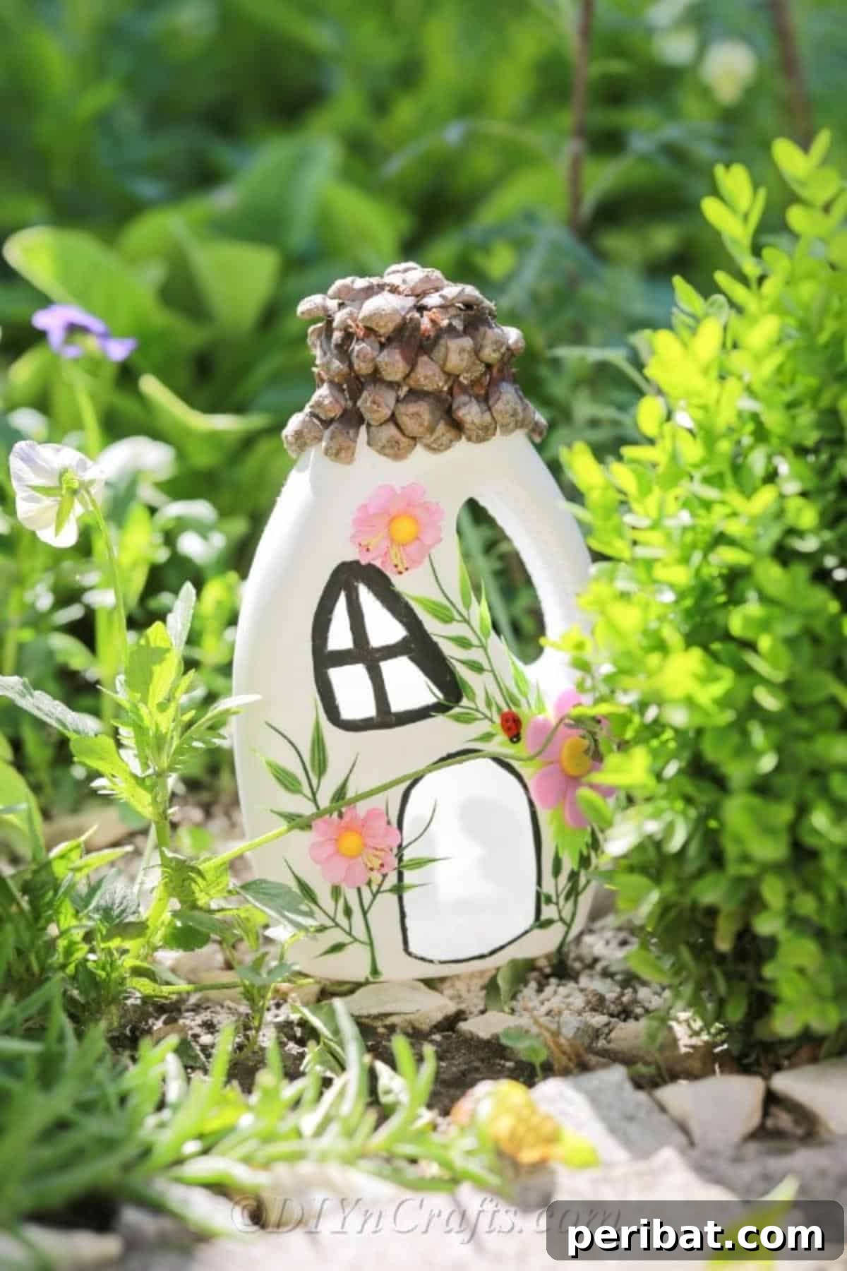 Finished fairy house crafted from a recycled bottle, nestled within a green garden setting, adorned with natural elements