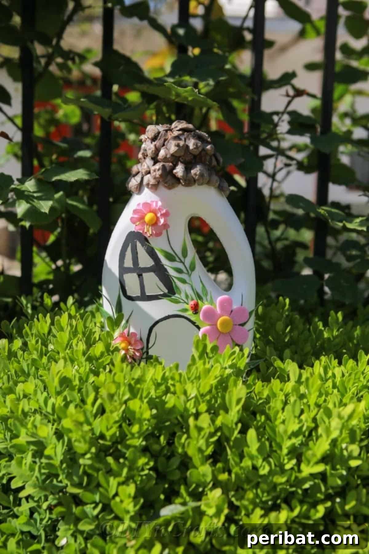 Upcycled fairy house adorning an evergreen bush, adding charm to the garden with its handmade appeal