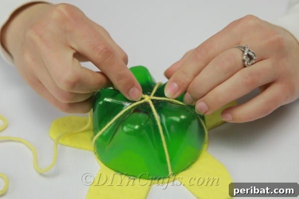 Decoratively sewing yarn over the plastic soda bottle bottom and through the foam turtle body.