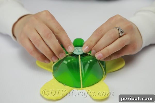 Gluing a small, colorful button onto the center of the plastic bottle 'shell' for a decorative touch.