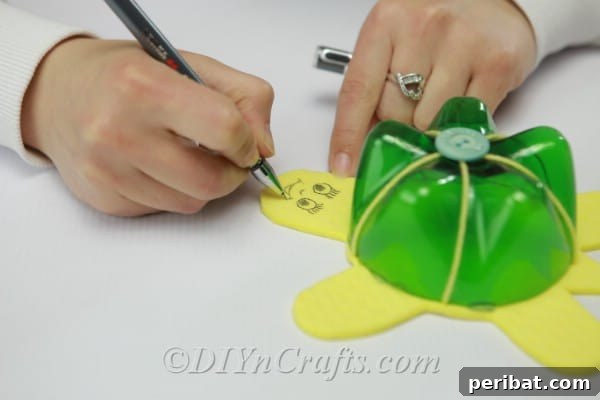 Drawing an expressive face, including eyes and a mouth, onto the yellow foam turtle's head with a black marker.