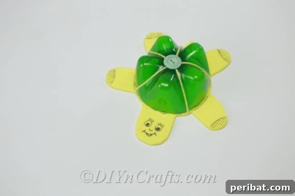 The finished green and yellow plastic bottle turtle, floating perfectly in water, showcasing the completed craft.