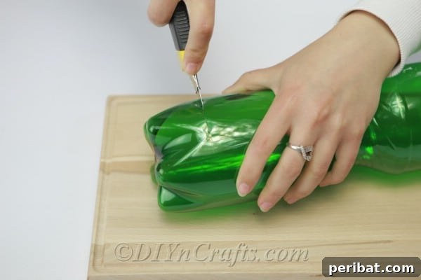 Adult hands carefully cutting the bottom off a plastic soda bottle with a craft knife.