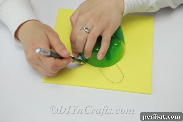 Sketching the head, legs, and tail onto the yellow craft foam, expanding from the traced bottle bottom.