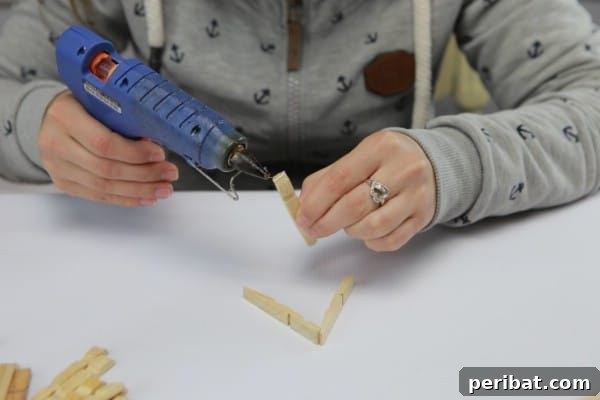 Applying hot glue to secure clothespin triangles