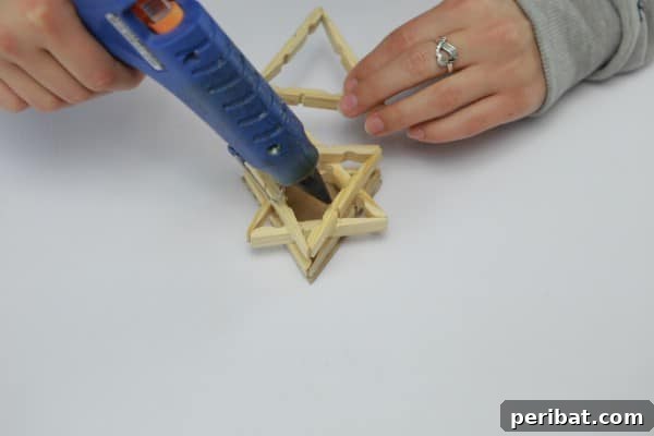 Adding more layers of clothespin triangles to build the lamp structure