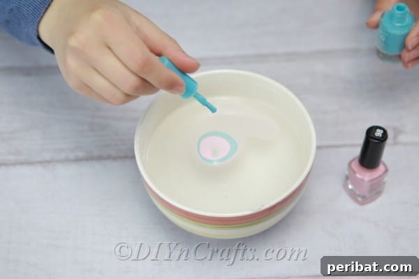 More drops of various nail polish colors being added to the water, layering to create depth.