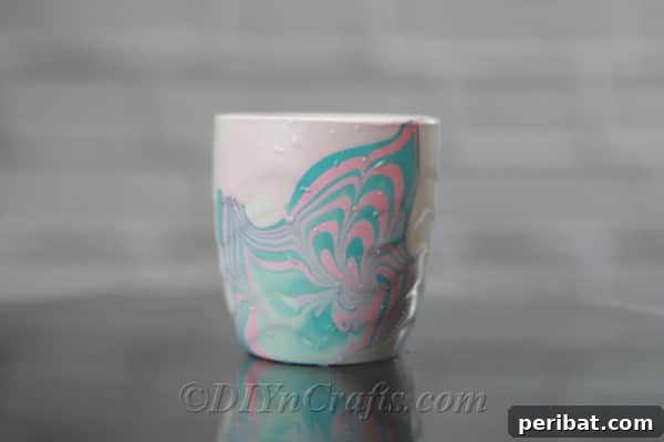 A finished white coffee cup showcasing an elegant pink and blue marbling pattern.