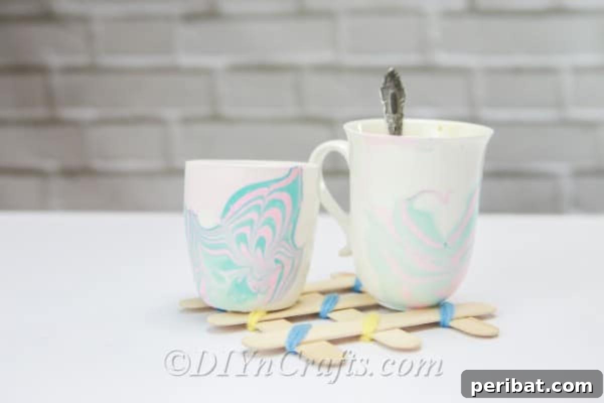 Nail Polish Marble Cup Magic 4 Two elegantly marbled coffee mugs with a matching spoon, ready for a stylish coffee break.