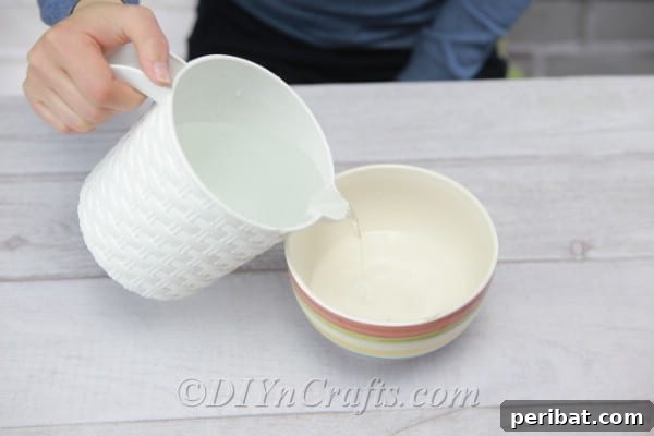 A clear glass bowl being filled with room temperature water, preparing for the marbling process.