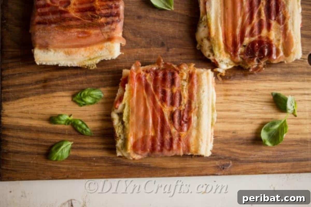 Pesto Perfection Grilled Cheese 3 Two finished pesto grilled cheese sandwiches, perfectly golden brown and sliced in half, showcasing the melted cheese and colorful layers