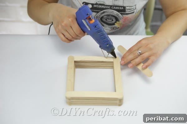 Build up the walls of the bird feeder by continuously stacking alternating craft sticks.