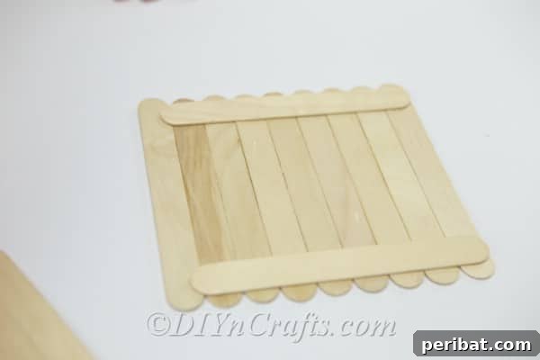 Continue building the roof section by adding perpendicular craft sticks.
