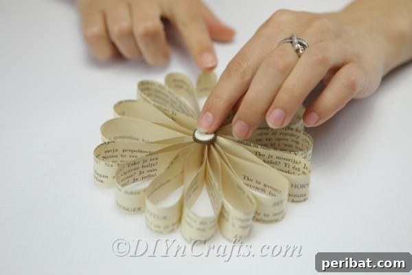 Glue a decorative button onto the center of the book page flower.