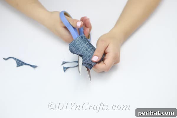 Cut a scalloped edge along the folded denim strip to form petal shapes.