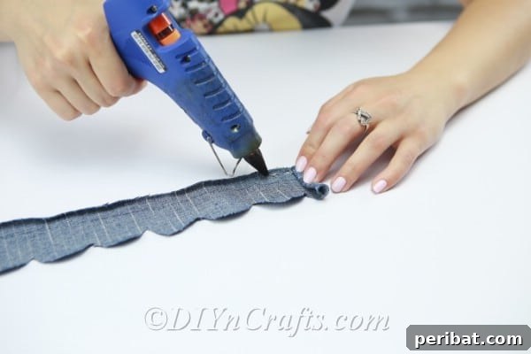 Blooming Denim Art 17 Apply hot glue along the straight edge of the denim strip before rolling.