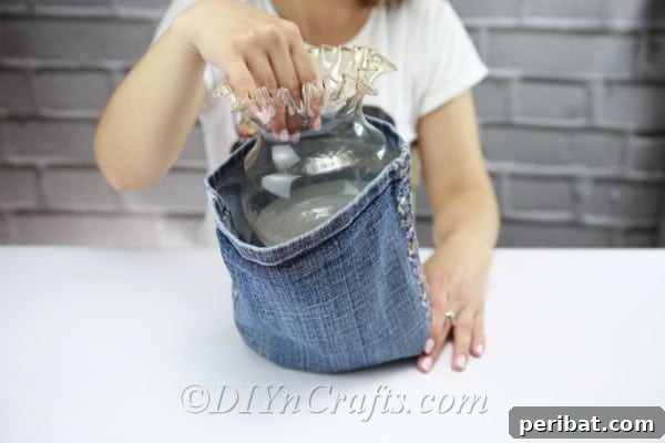 Insert the vase into the prepared denim cover, ensuring a snug fit.