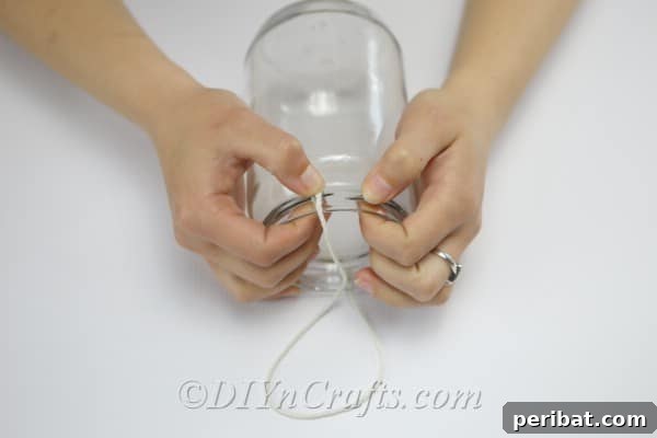 Eski Kavanoza Yeni Hayat: Duvarına Asılan Çiçek Şöleni 11 Form a hanging loop with twine around the top of the jar.
