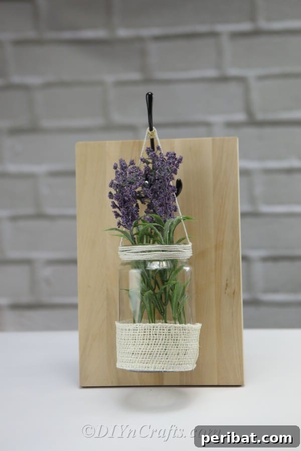 Hang the decorated jar from the hook on the wooden backing.