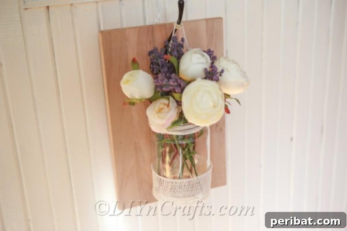 Eski Kavanoza Yeni Hayat: Duvarına Asılan Çiçek Şöleni 3 Completed rustic wall vase filled with beautiful flowers, ready for display.