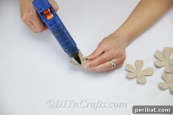 Craft Exquisite Roses from Recycled Egg Cartons 13 Apply a small dab of glue in the center of one petal piece to begin forming the rose's core.