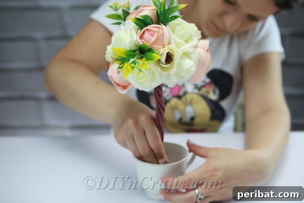 Place the assembled topiary tree trunk firmly into the Styrofoam base inside the cup.