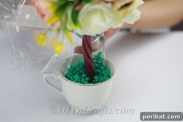 Pour decorative rocks into the cup to cover the Styrofoam and stabilize the arrangement.