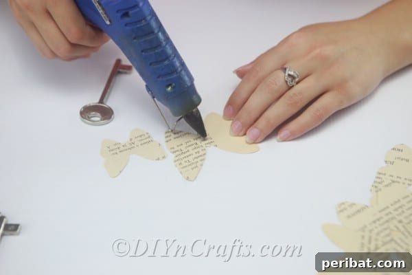 DIY Rustic Butterfly Art from Upcycled Books 13 Apply hot glue to the top of one of your larger butterfly shapes for layering.