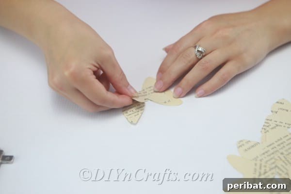 Attach the smaller butterfly shape precisely on top of the larger one to create a 3D effect.