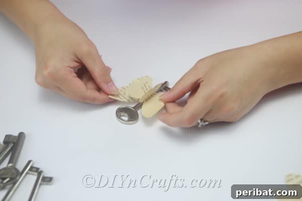 Attach a vintage key securely to the center of a paper butterfly using hot glue.