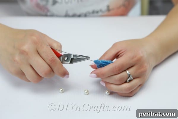 Create Your Own Trendy Yarn Tassel Earrings 12 Insert the jewelry wire into the tassel's top, ensuring it protrudes straight out for bead placement.