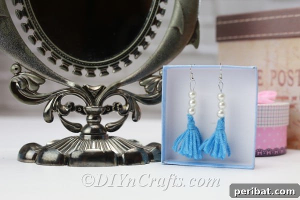 Create Your Own Trendy Yarn Tassel Earrings 17 A curated display of yarn tassel earrings in a decorative box, alongside an ornate mirror, emphasizing their artistic charm.