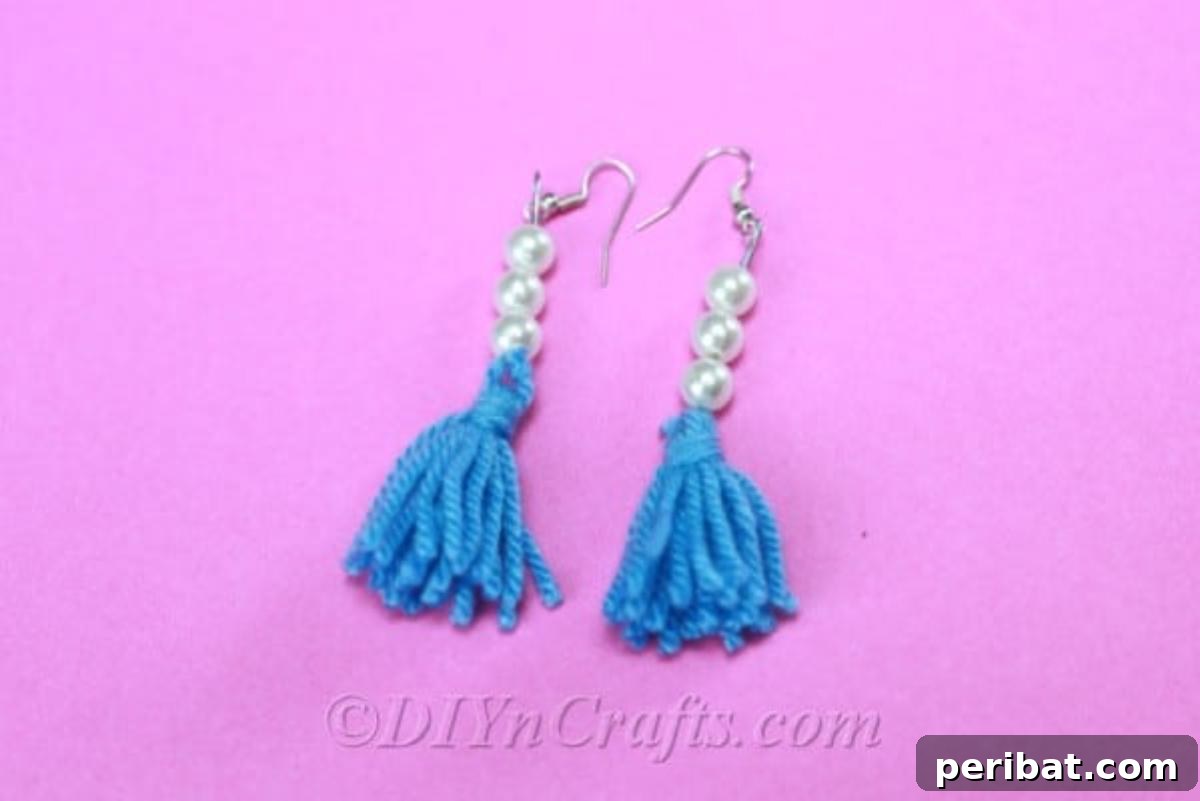 Create Your Own Trendy Yarn Tassel Earrings 6 A pair of beautifully crafted yarn tassel earrings with intricate beadwork, displayed against a soft pink backdrop, highlighting their vibrant colors.