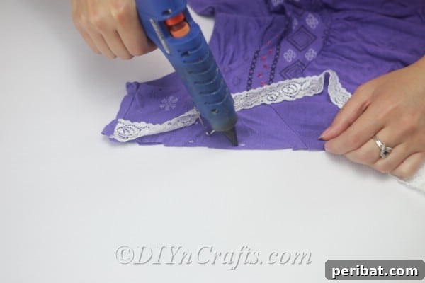 Use hot glue to attach the lace firmly along the cut edges of the T-shirt.