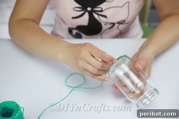 Vibrant Painted Jars for Summer Drinks 7 Begin winding green string around the base of the glass jar, securing it with hot glue.