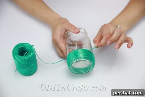 Vibrant Painted Jars for Summer Drinks 9 Continue wrapping the green string neatly around the jar until you reach the desired height, forming the base.