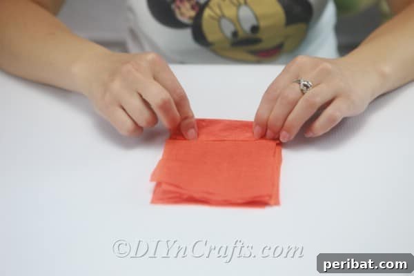 Initiating the accordion fold on one pile of tissue paper strips, folding them uniformly back and forth.