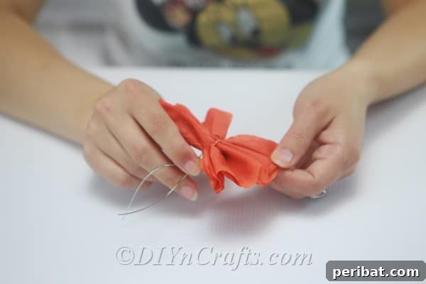 Tying a piece of gardening wire securely around the pinched middle section of the tissue paper to form the center of the flower.