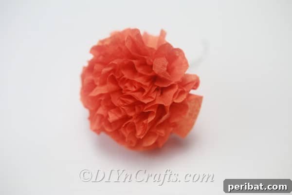 A single, perfectly shaped small tissue paper flower after the trimming and fluffing process is complete.