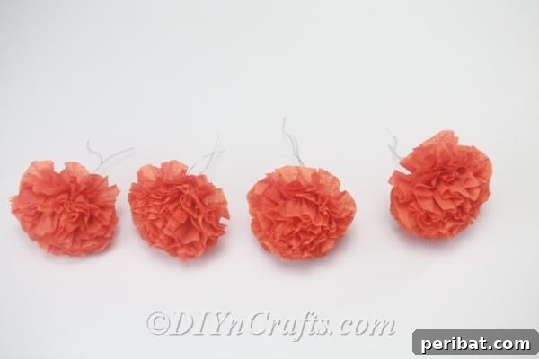 Display of four completed small tissue paper flowers, prepared to be joined together to form a larger pom-pom.