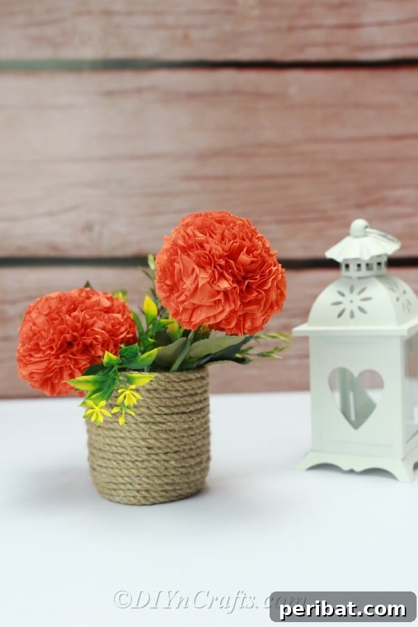 An elegant arrangement featuring two beautifully crafted tissue paper ball flowers, complemented by faux greenery, displayed in a basket against a warm wooden backdrop.
