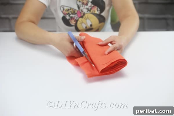 Further folding the strips and cutting them again to achieve many smaller, uniform tissue paper pieces.