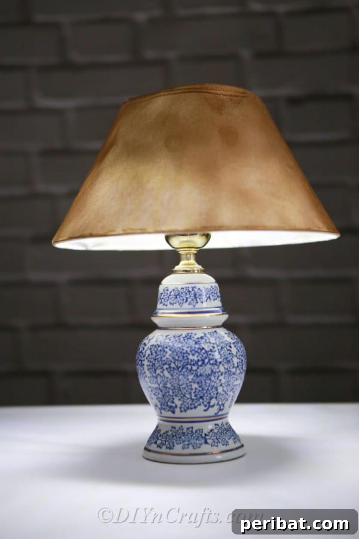 A close-up view of the finished DIY solar garden lamp, glowing softly on a table, showcasing its vintage-inspired spray-painted lampshade.