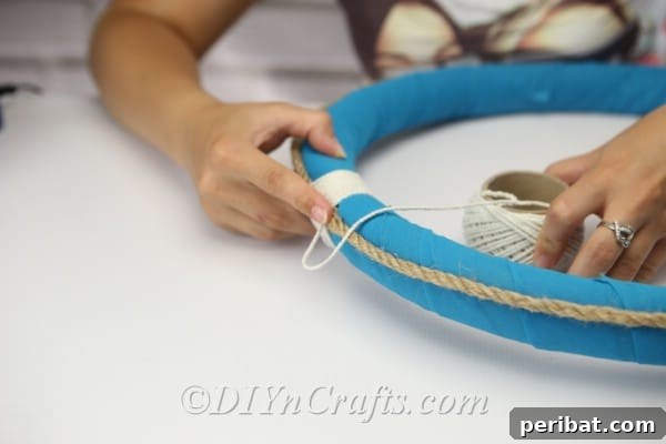 Coastal Elegance: Craft Your Perfect Summer Wreath 16 Begin wrapping the white string tightly and evenly around the wreath to conceal the rope ends.
