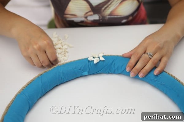 Coastal Elegance: Craft Your Perfect Summer Wreath 19 Continue placing shells along the bottom, creating a natural, wave-like pattern.