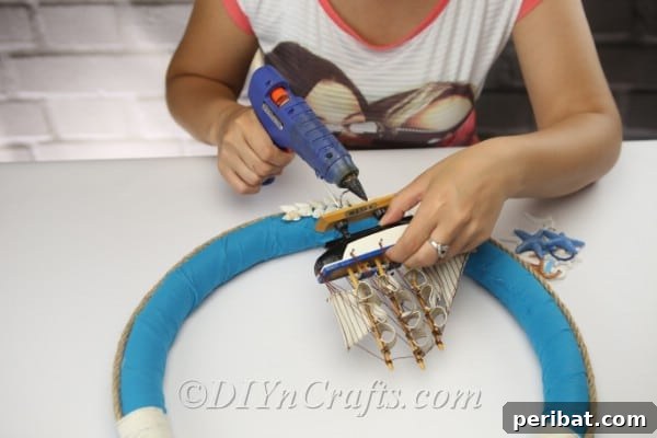 Coastal Elegance: Craft Your Perfect Summer Wreath 24 Hot glue your miniature ship ornament directly onto the wreath, just above the shell embellishments.